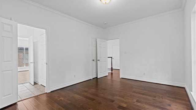 unfurnished bedroom with dark wood-type flooring, crown molding, baseboards, and ensuite bathroom