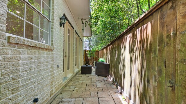 view of side of property with a patio area, brick siding, and fence