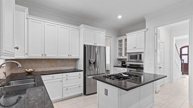 kitchen featuring stainless steel appliances, a sink, white cabinetry, tasteful backsplash, and dark stone counters