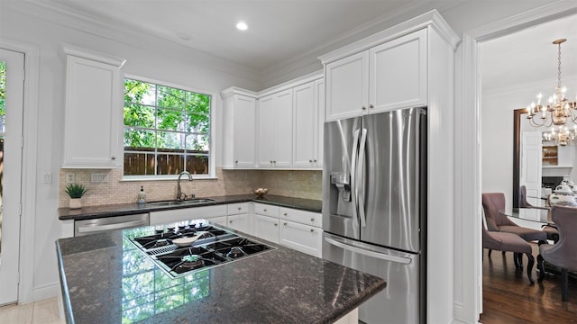 kitchen featuring appliances with stainless steel finishes, a chandelier, a sink, decorative backsplash, and a kitchen island