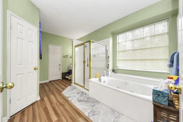 bathroom with wood finished floors, a whirlpool tub, and a shower stall