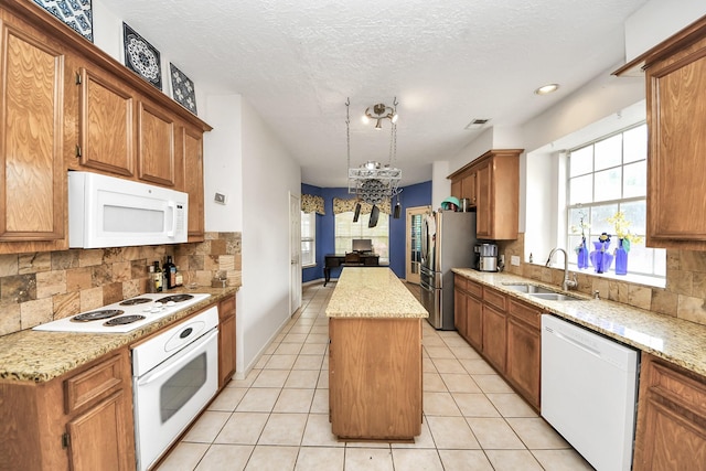 kitchen with white appliances, a sink, a center island, a chandelier, and backsplash