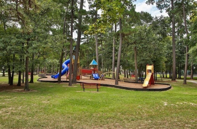 communal playground with a lawn and view of wooded area