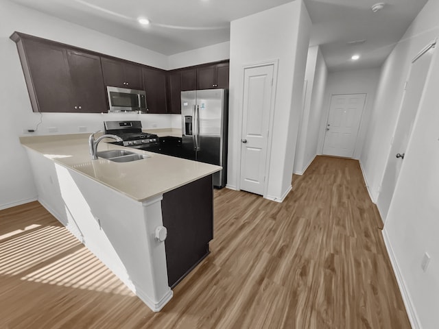 kitchen with appliances with stainless steel finishes, light wood finished floors, light countertops, dark brown cabinetry, and baseboards