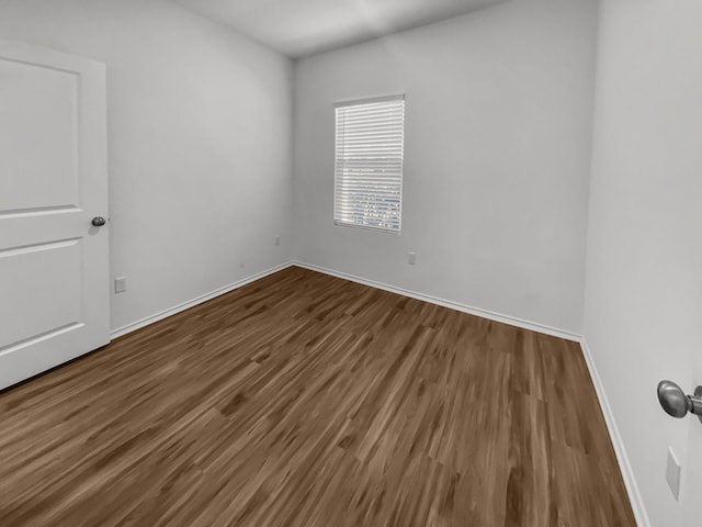 empty room featuring wood finished floors and baseboards
