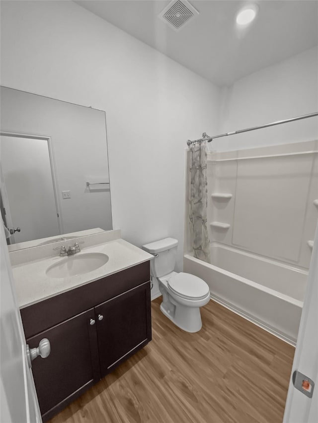 full bath with wood finished floors, vanity, shower / bath combo, and toilet