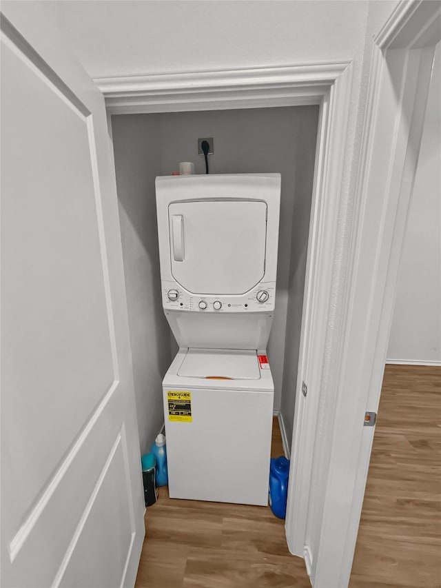 washroom featuring stacked washer and clothes dryer and wood finished floors