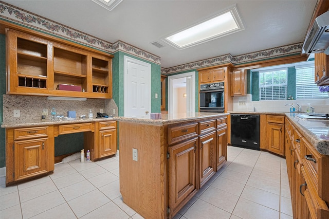 kitchen with black appliances, light tile patterned floors, a kitchen island, tasteful backsplash, and light stone counters
