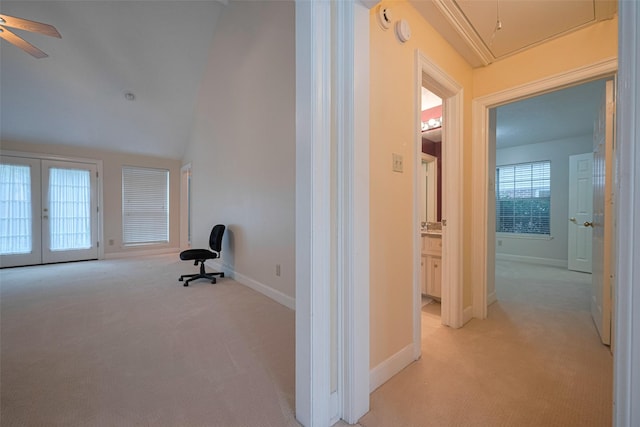 corridor with attic access, light carpet, french doors, baseboards, and lofted ceiling