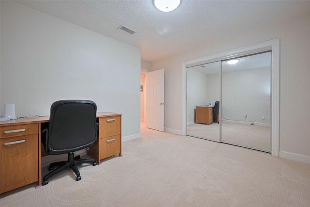 office with light colored carpet, baseboards, and a textured ceiling