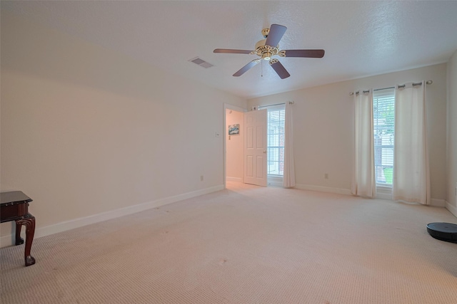 empty room featuring baseboards, light colored carpet, and a ceiling fan