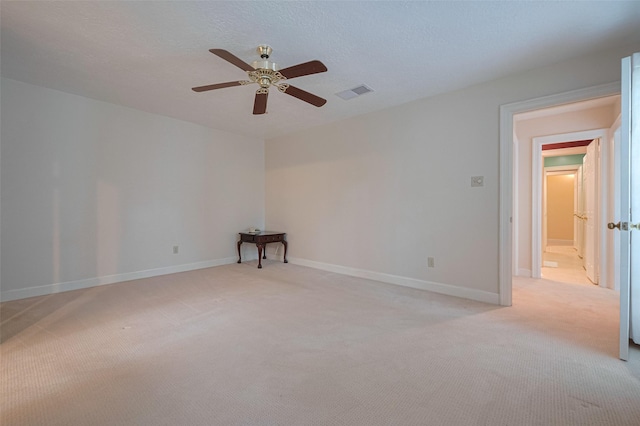 spare room featuring light carpet, a ceiling fan, and baseboards