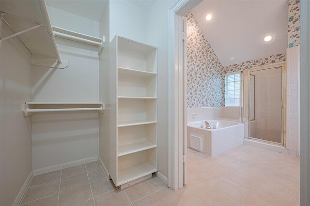 full bath with a spacious closet, vaulted ceiling, a shower stall, a garden tub, and baseboards