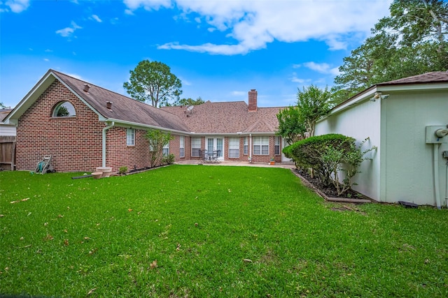 back of house featuring a lawn, brick siding, a chimney, and a patio area