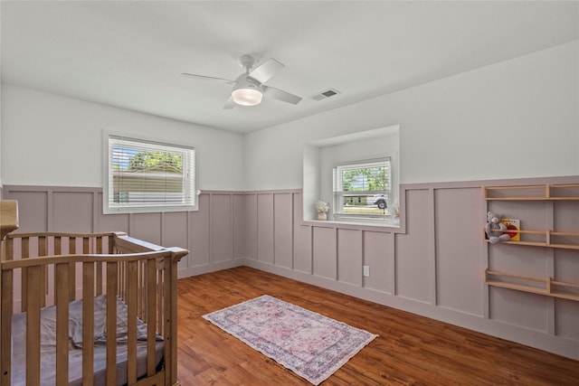 bedroom featuring a wainscoted wall, wood finished floors, and a ceiling fan