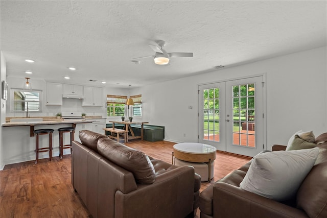 living room with wood finished floors, french doors, a ceiling fan, recessed lighting, and a textured ceiling