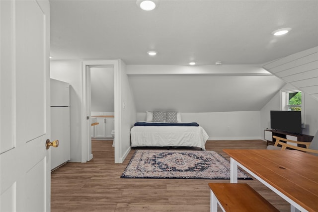 bedroom featuring lofted ceiling, wood finished floors, baseboards, recessed lighting, and freestanding refrigerator