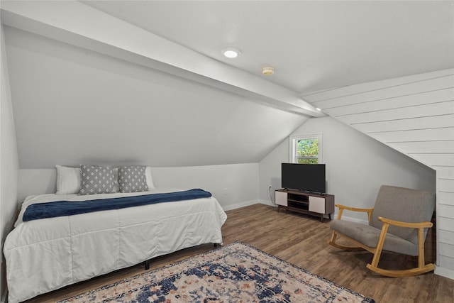 bedroom featuring baseboards, wood finished floors, and lofted ceiling