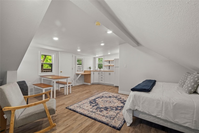 bedroom with freestanding refrigerator, light wood-style floors, recessed lighting, multiple windows, and a textured ceiling