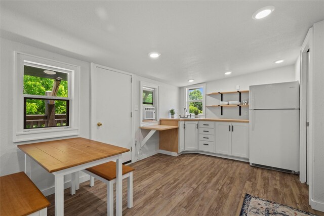 kitchen with freestanding refrigerator, wood finished floors, a sink, white cabinetry, and light countertops