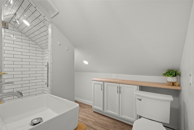 full bath with wood finished floors, vaulted ceiling, toilet, and baseboards