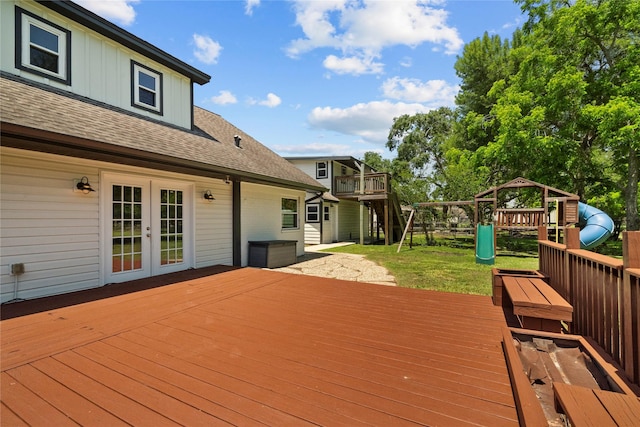 wooden deck with a playground, french doors, and a lawn