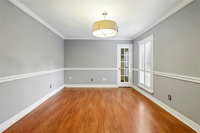unfurnished room featuring wood finished floors, crown molding, and baseboards