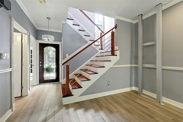 entryway featuring stairs, wood finished floors, crown molding, and baseboards
