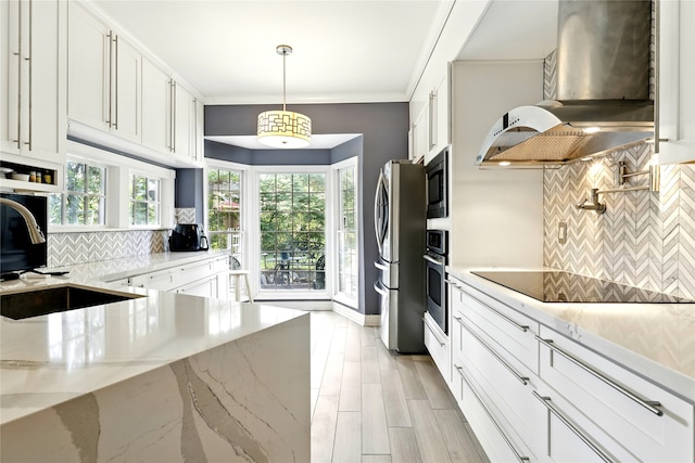 kitchen featuring wall chimney range hood, stainless steel appliances, backsplash, white cabinets, and ornamental molding