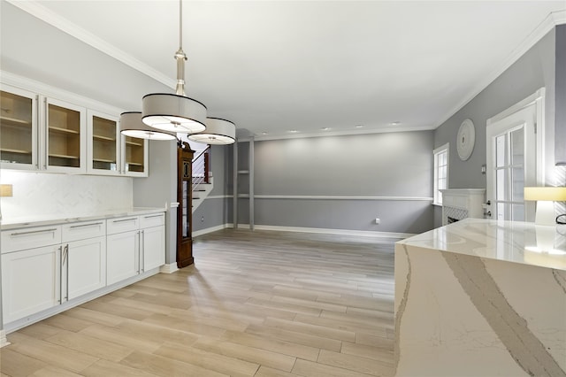 kitchen featuring ornamental molding, light stone countertops, white cabinets, glass insert cabinets, and light wood-type flooring