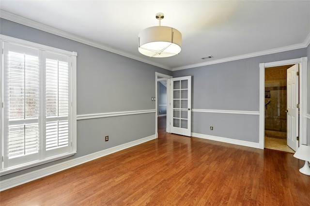 spare room with wood finished floors, baseboards, crown molding, and french doors