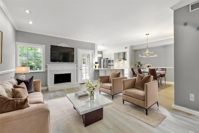living room featuring light wood-style flooring, recessed lighting, a fireplace, baseboards, and crown molding