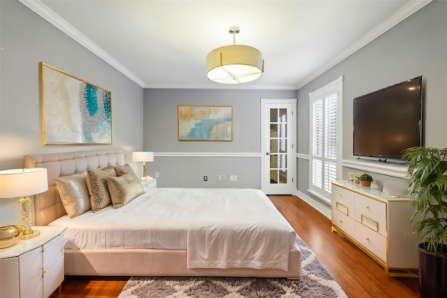 bedroom with ornamental molding and wood finished floors