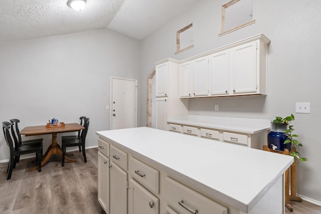 31311 N Head Dr, Spring, TX 77386 - kitchen with vaulted ceiling, light countertops, light wood-type flooring, a kitchen island, and a textured ceiling