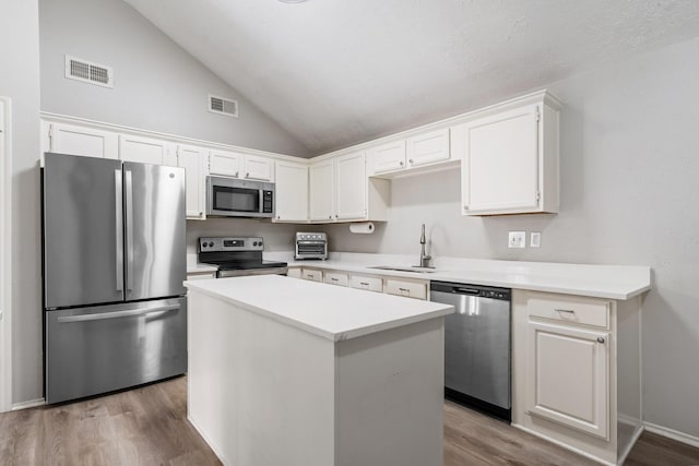 31311 N Head Dr, Spring, TX 77386 - kitchen with stainless steel appliances, a sink, wood finished floors, white cabinets, and a kitchen island