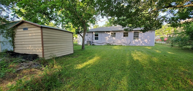 10341 Caxton St, Houston, TX 77016 - rear view of house featuring a yard, an outdoor structure, central AC unit, and a storage unit