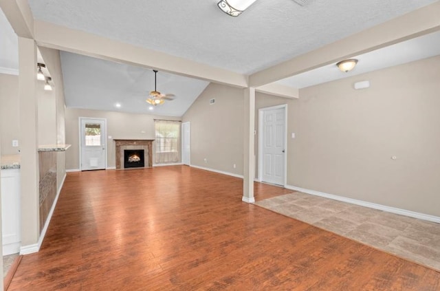 unfurnished living room with a ceiling fan, wood finished floors, baseboards, and a warm lit fireplace