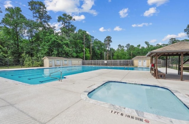 community pool featuring fence, a patio area, a shed, and an outdoor structure