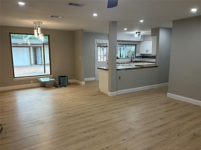 unfurnished living room featuring healthy amount of natural light, light wood finished floors, a sink, and recessed lighting