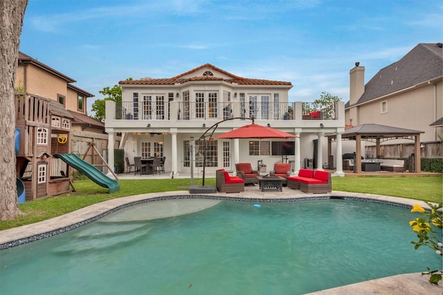back of property with an outdoor living space with a fire pit, stucco siding, a balcony, and a patio