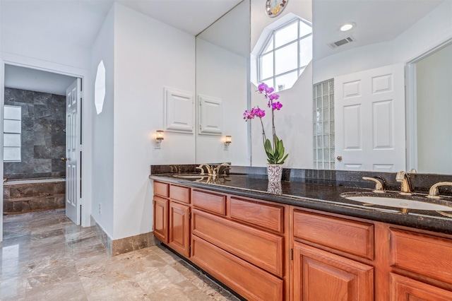 full bath featuring double vanity, marble tiled flooring, a bath, and baseboards