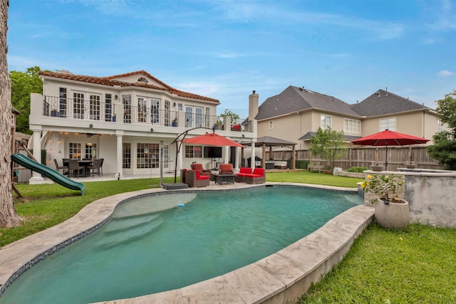 rear view of property with an outdoor hangout area, french doors, a patio, stucco siding, and a balcony