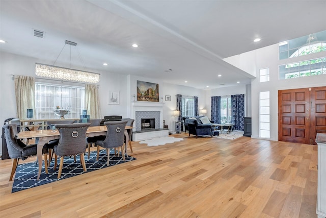 dining area featuring light wood-style flooring, recessed lighting, a fireplace with raised hearth, and a chandelier