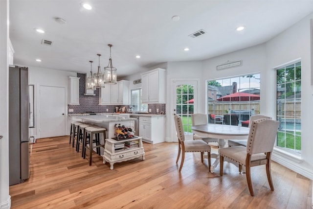dining room with plenty of natural light, light wood-type flooring, recessed lighting, and a chandelier