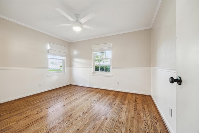 unfurnished room with wood finished floors, crown molding, a ceiling fan, and wainscoting