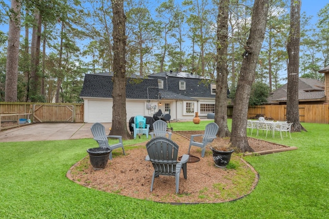 back of house with a shingled roof, a garage, driveway, and a patio area