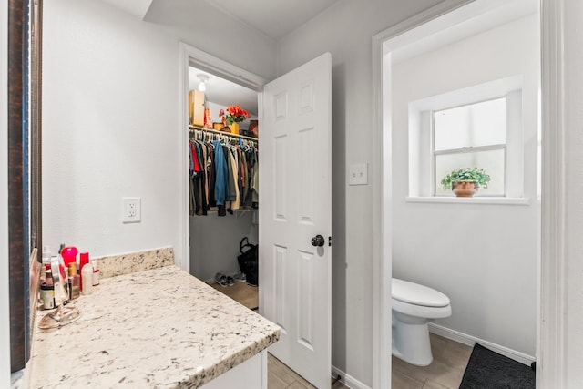 bathroom with toilet, vanity, and baseboards