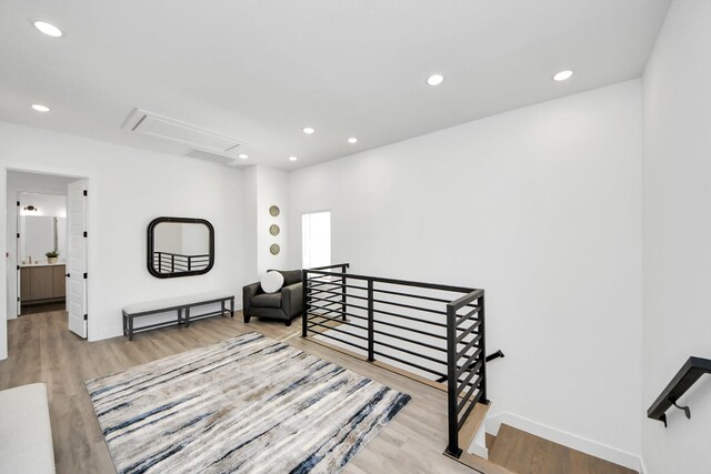 living area with an upstairs landing, light wood-style flooring, recessed lighting, baseboards, and attic access