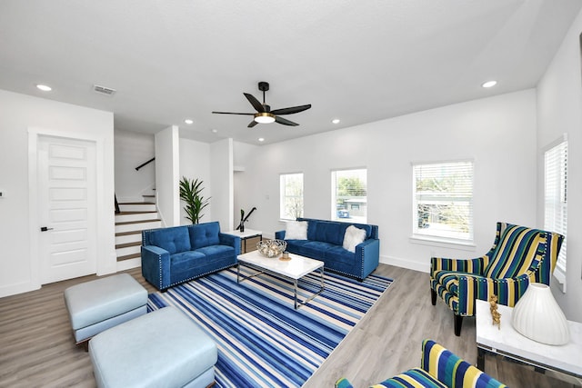 living area with wood finished floors, a ceiling fan, stairs, recessed lighting, and baseboards