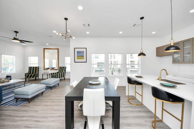 dining room featuring a ceiling fan, recessed lighting, light wood-style floors, baseboards, and a chandelier